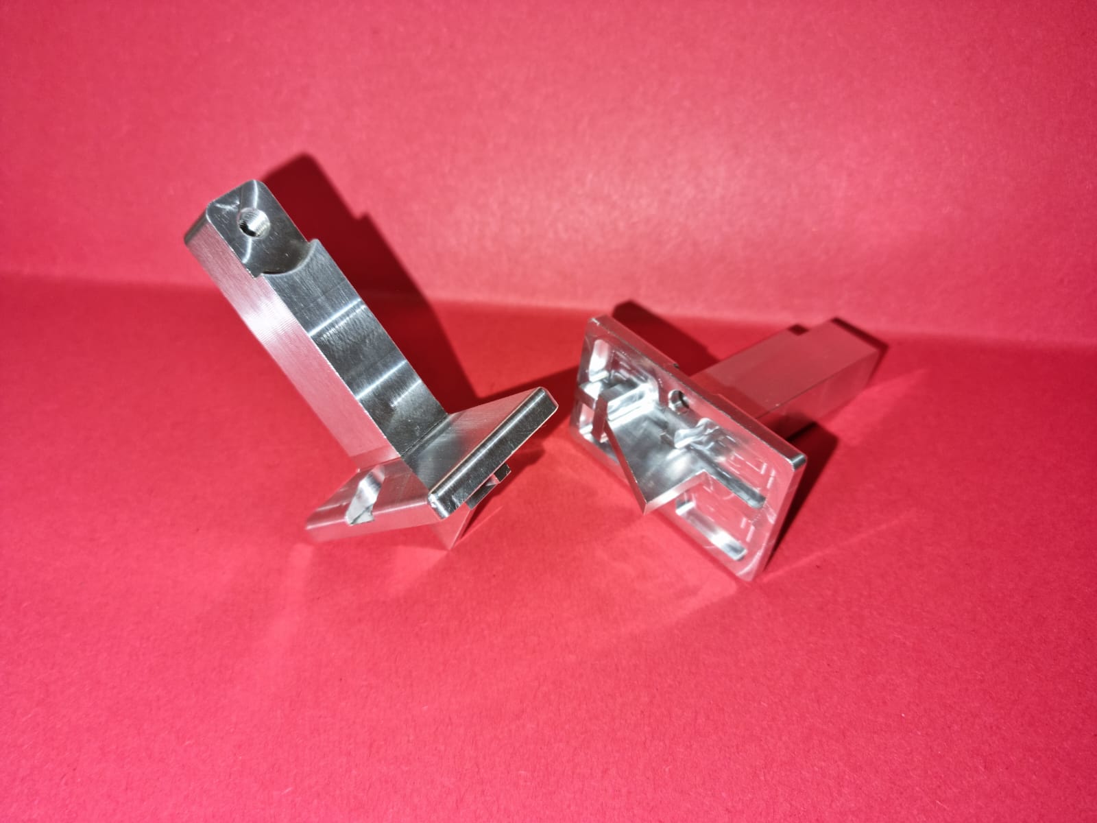 Deux supports aluminium fraisés de forme complexe sur fond rouge